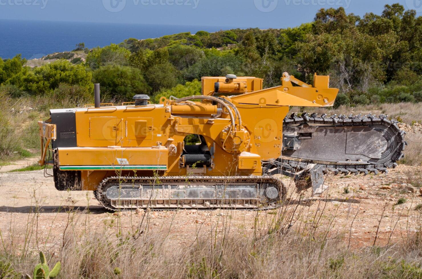 Powerful Trencher Machine on a Coastal Landscape, with sea View on backgtound photo