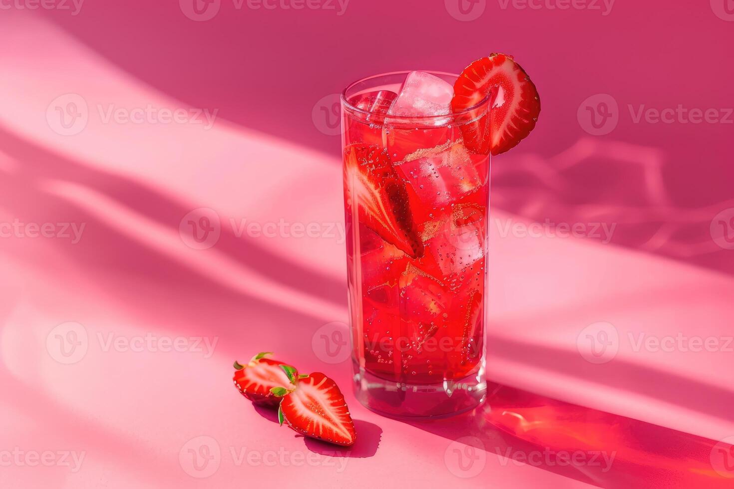 A Glass of Red Strawberry Drink with Ice and Slices on a Pink Background photo