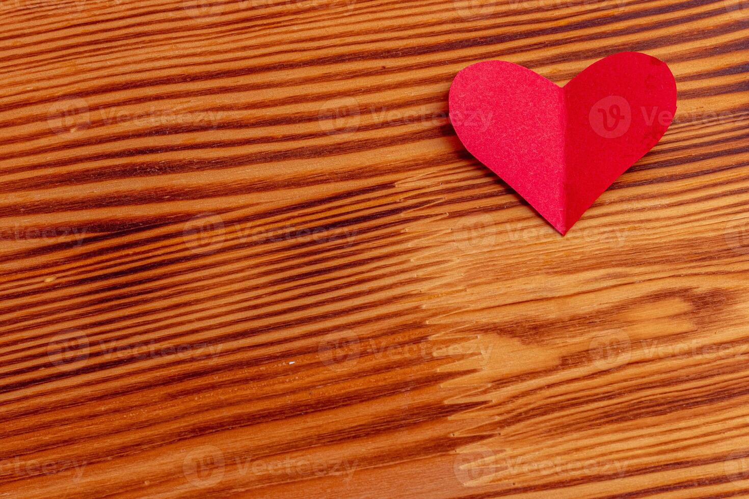 Hand cut heart from red paper on wooden background photo