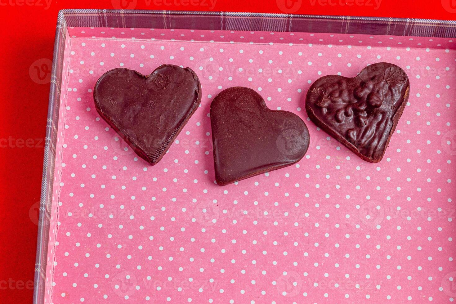 Horizontally, hearts made of dark chocolate on a pink box background photo