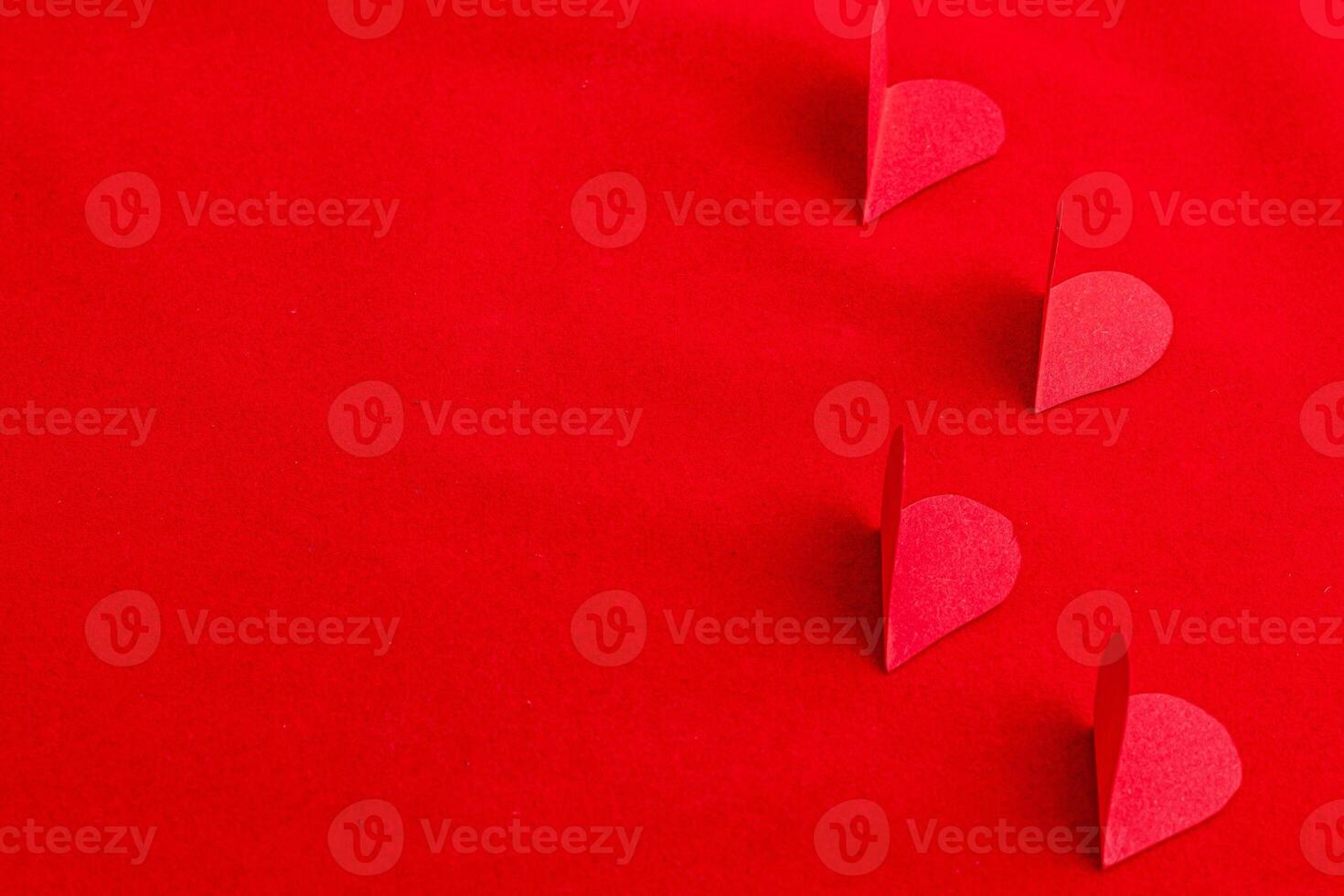 Hand cut paper hearts on a red background photo