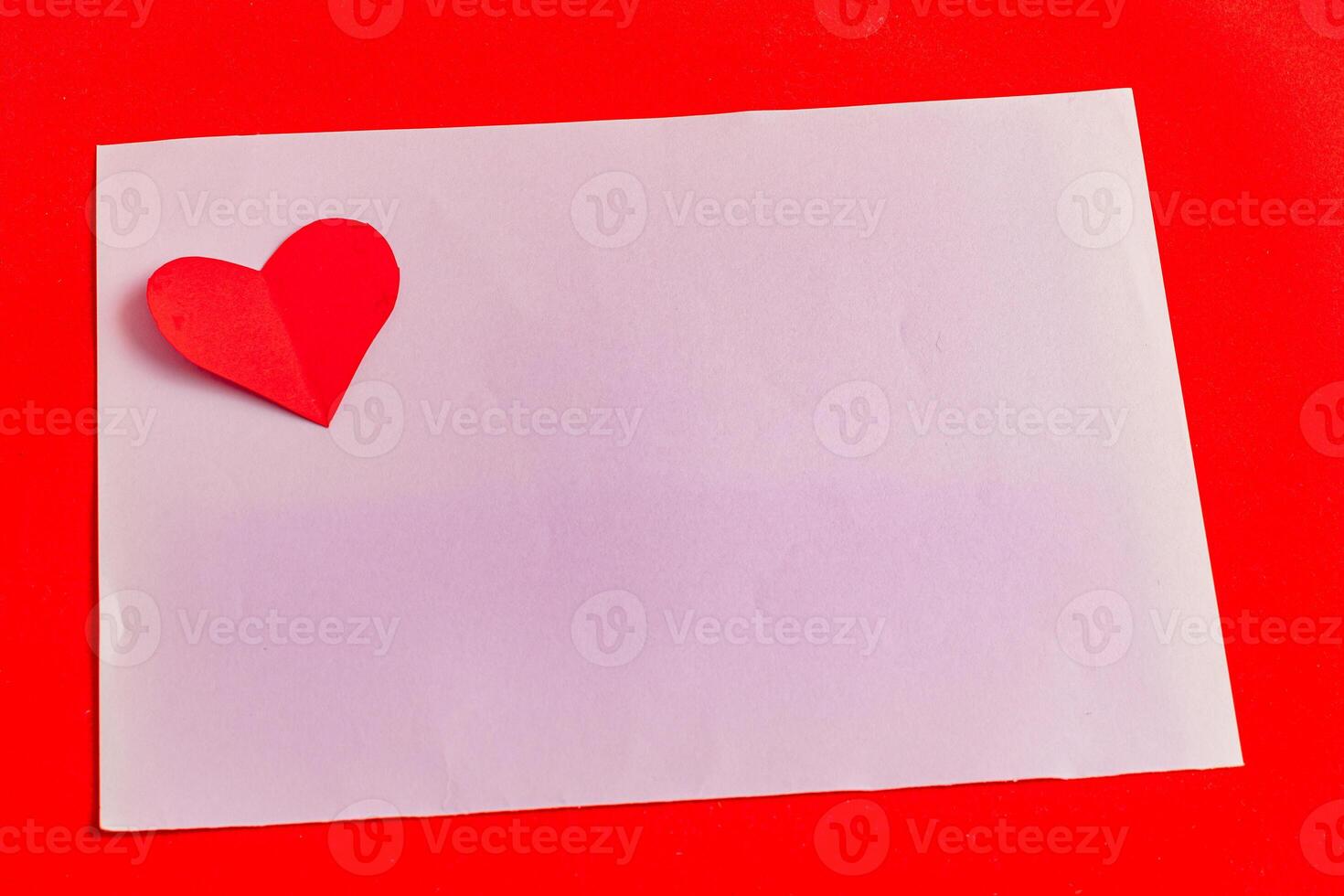 A love note with a paper heart on a purple leaf on a bright red background photo