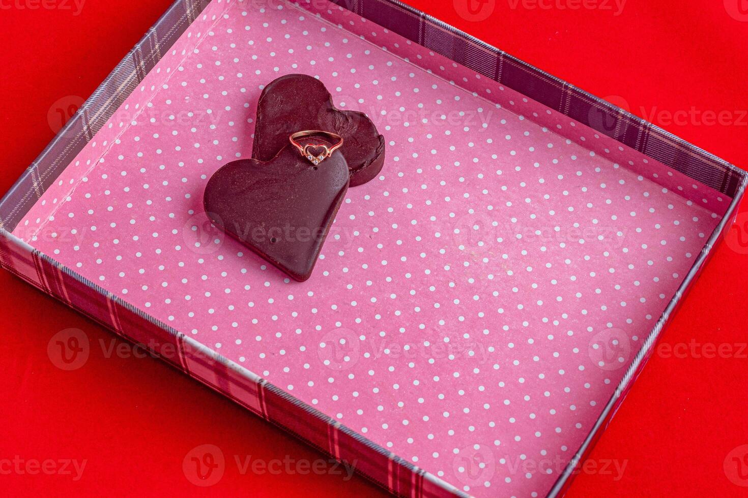 Chocolate hearts in a pink box on a red background photo