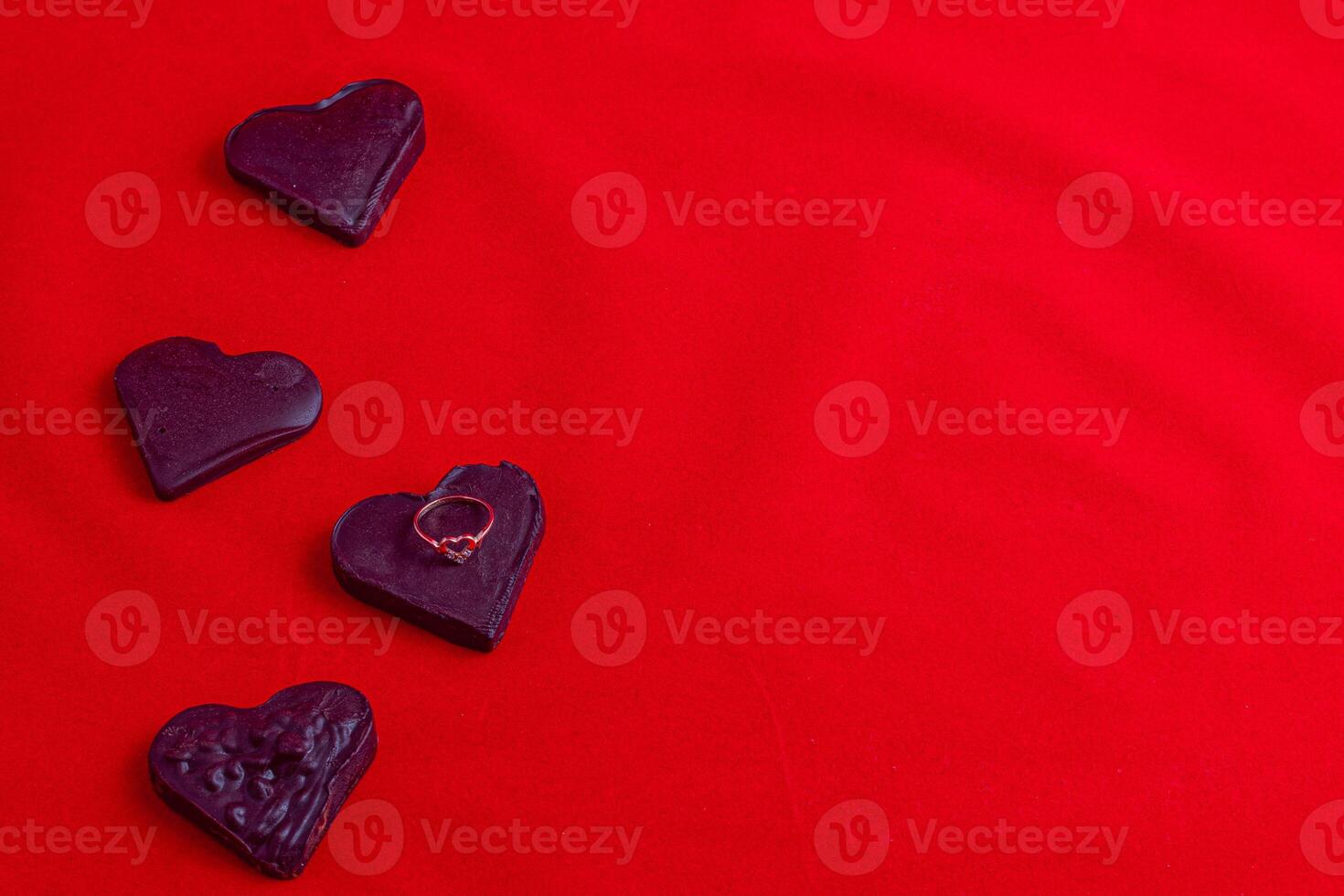 Hearts made of black chocolate with a ring on a red background, Valentine's Day photo