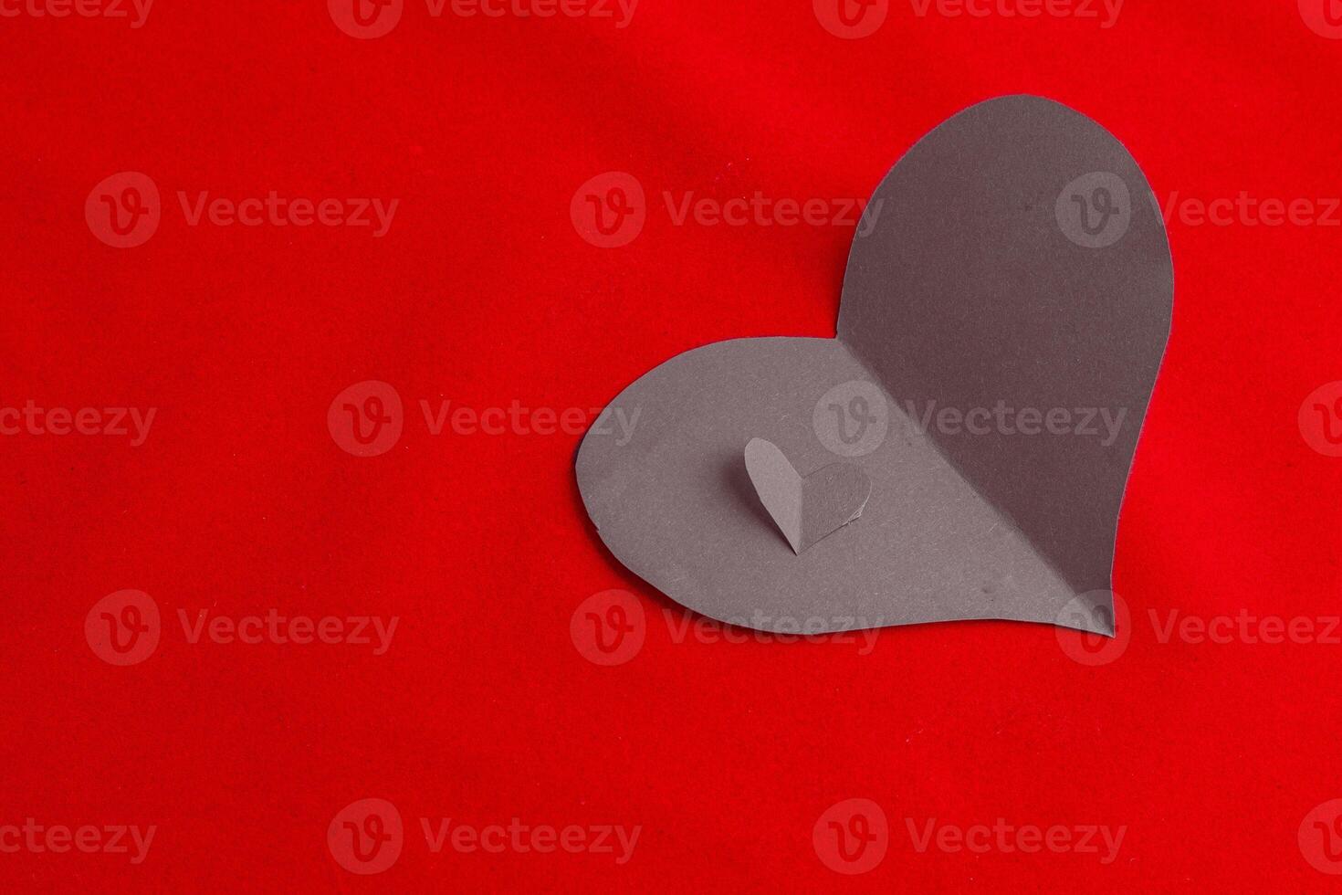 Two sad gray paper hearts on a red background, not mutual love photo