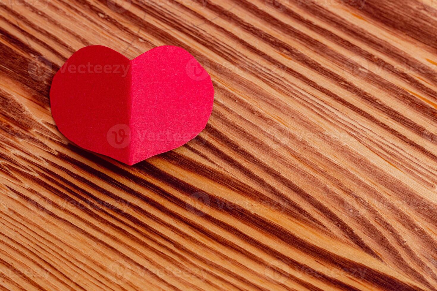 Hand cut heart from red paper on wooden background photo