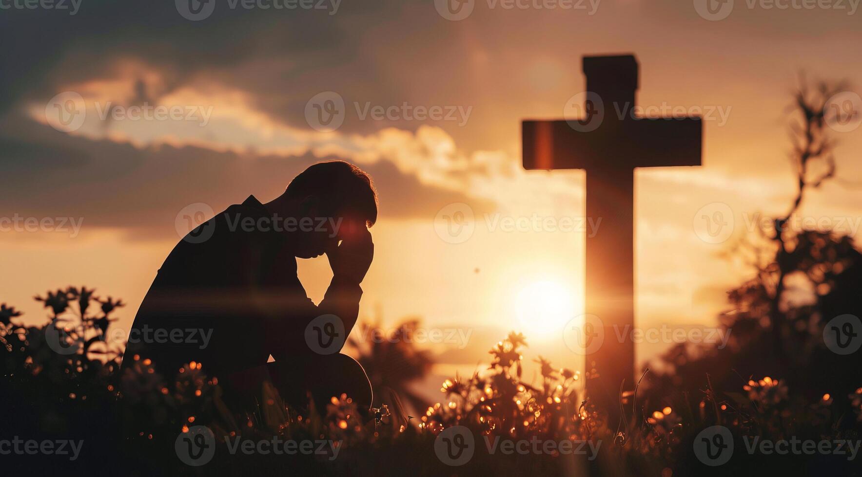 Devout faithful christian prays in front of the cross at a dramatic sunset with beautiful skies photo