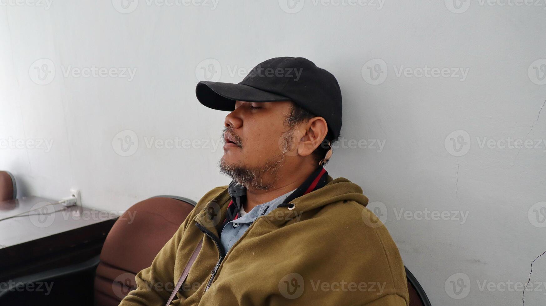 an adult man leeping exhaustedly leaning against the wall photo