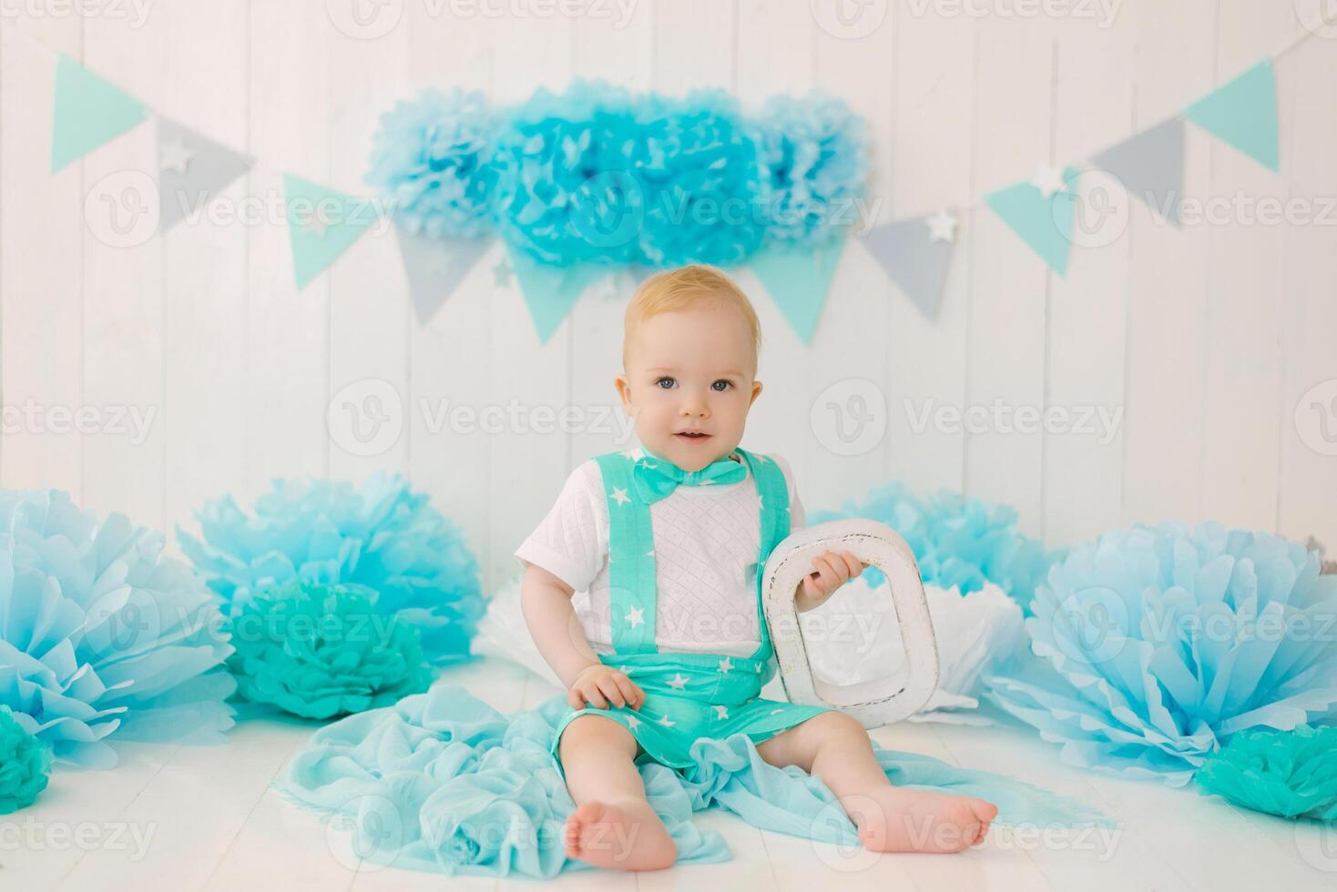 Birthday boy 1-year-old boy, babysitter with blue garlands and the letter O in a suit and bow tie photo