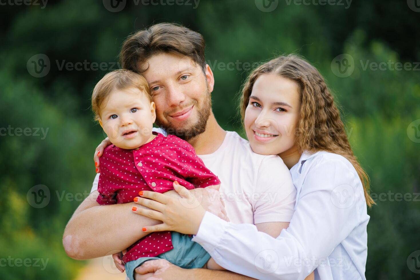A happy young beautiful family with a young son is enjoying a wonderful day in the summer park photo
