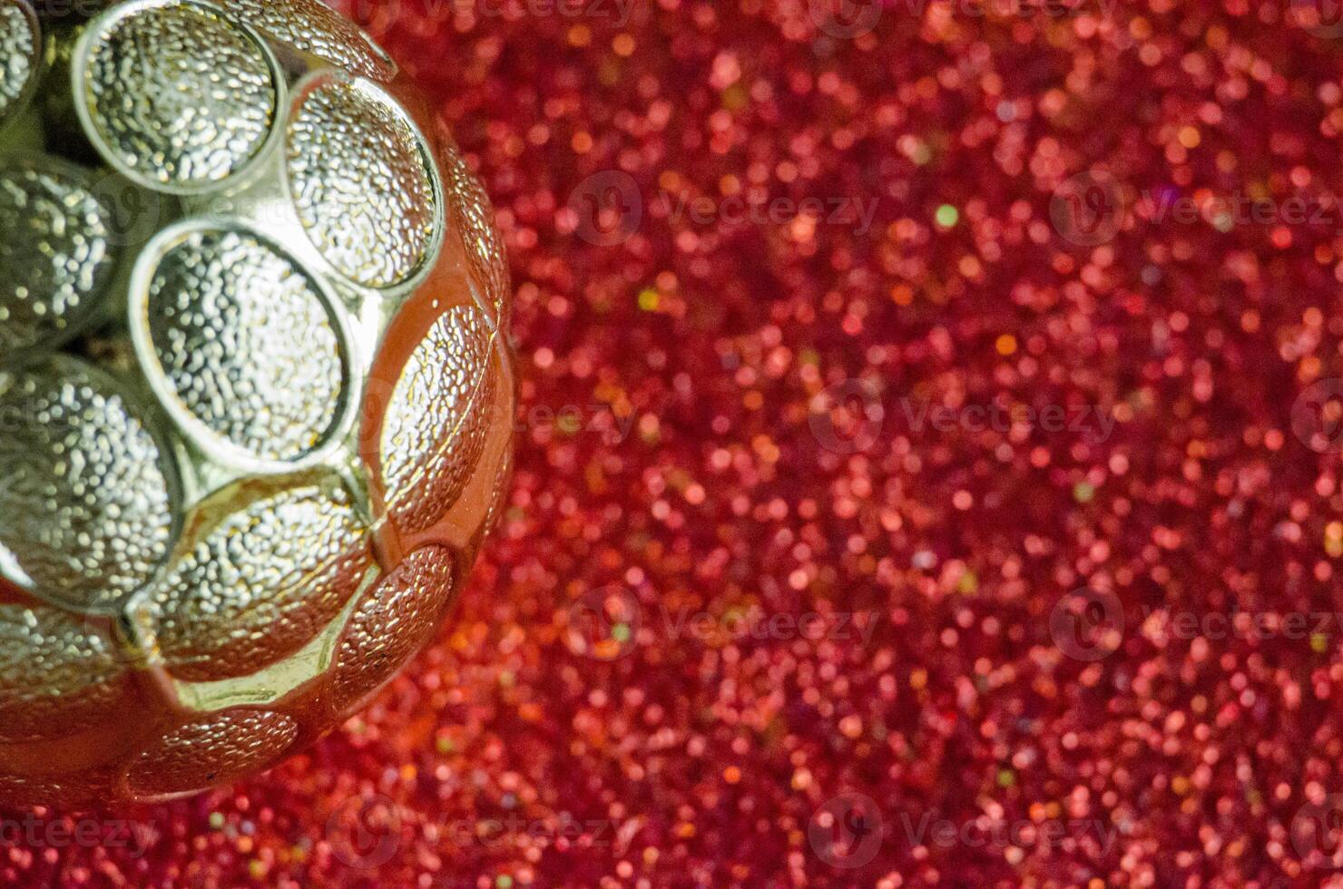 Close up of Golden Christmas ball on red background with customizable space for text or for wishes. photo