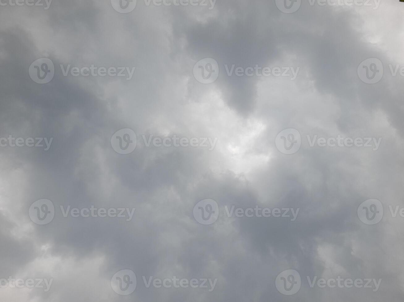 a cloudy sky with varying shades of gray, indicating an overcast day. The clouds are dense and layered, creating a moody and dramatic atmosphere, typical of an impending rainstorm or gloomy weather. photo