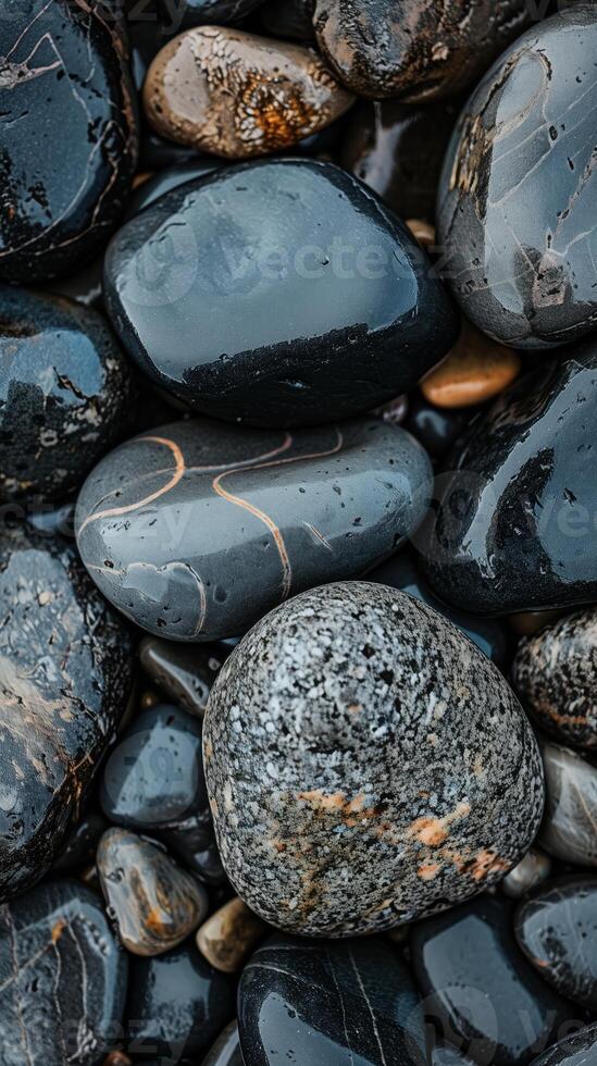 Smooth dark gray pebbles on a beach create a natural texture. Tranquil backgrounds and spa themes photo