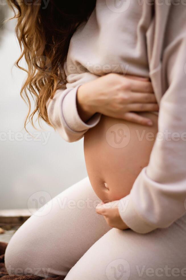 A pregnant woman is sitting on a blanket photo
