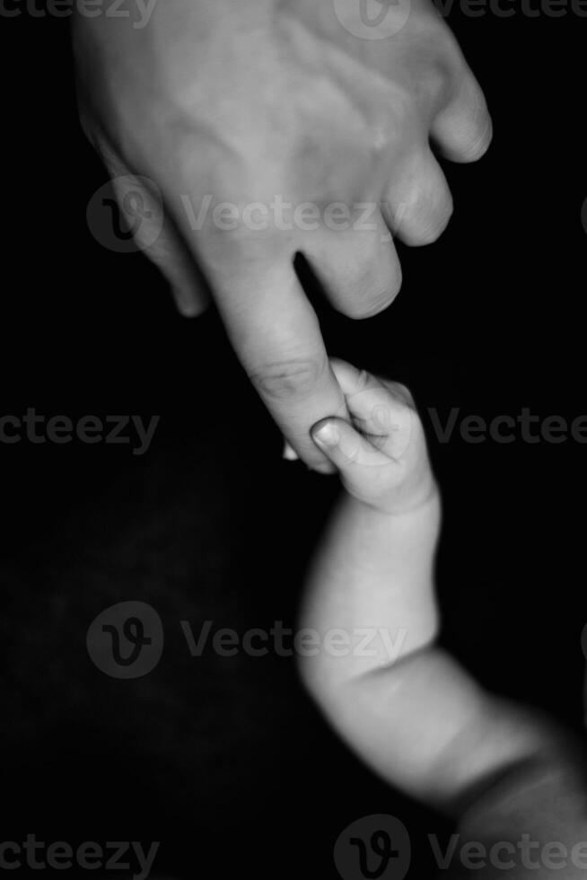A black and white photo of a baby's hand being held by a person