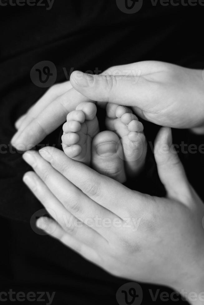 A black and white photo of a woman holding a baby's feet