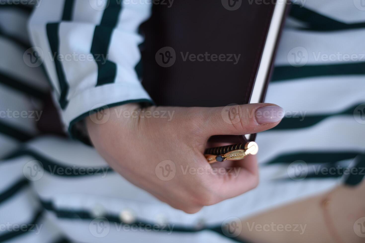 A person holding a book and a pen photo