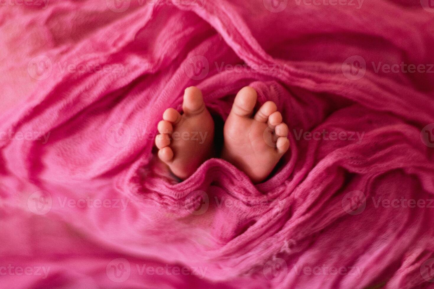 A baby's feet are covered in pink fabric photo