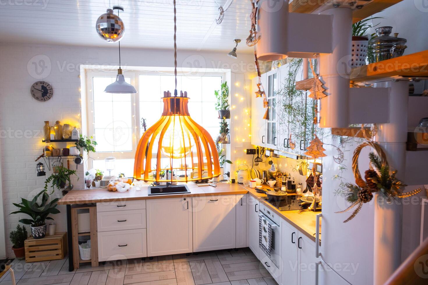 Christmas decor in white kitchen, modern village interior with a snowy Christmas tree and fairy lights. New Year, Christmas mood, cozy home, Metal modular staircase. photo
