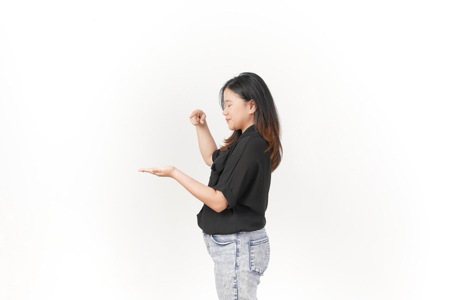 beautiful Asian woman poses with open hands, gesturing toward empty space to showcase a product against a white background photo