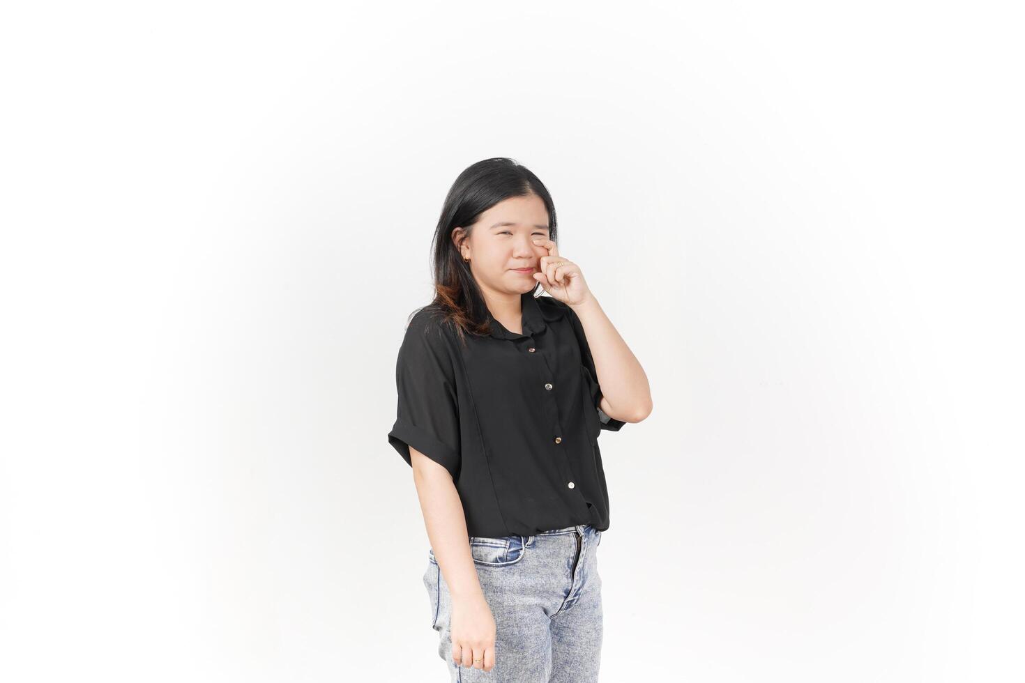 beautiful Asian woman poses with her fingers under her eyes, capturing a poignant crying expression against a white background photo
