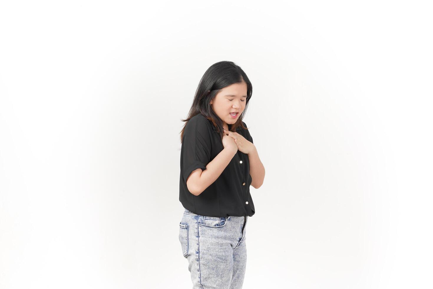 beautiful Asian woman holds her chest, displaying discomfort, against a clean white background photo