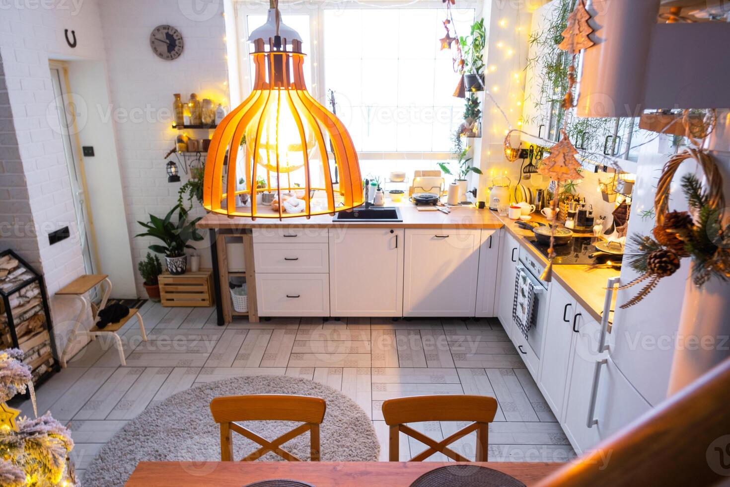 Christmas decor in white kitchen, modern rustic interior with a snowy Christmas tree and gold fairy lights. New Year, Christmas mood, cozy home. photo