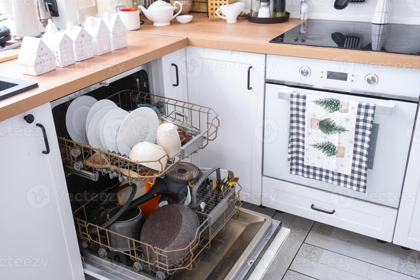 A lot of dirty dishes in the dishwasher in the festive kitchen. Helping the hostess, economy and ecology. Cleaning in the kitchen for the holidays of Christmas and New Year, after the feast and guests photo