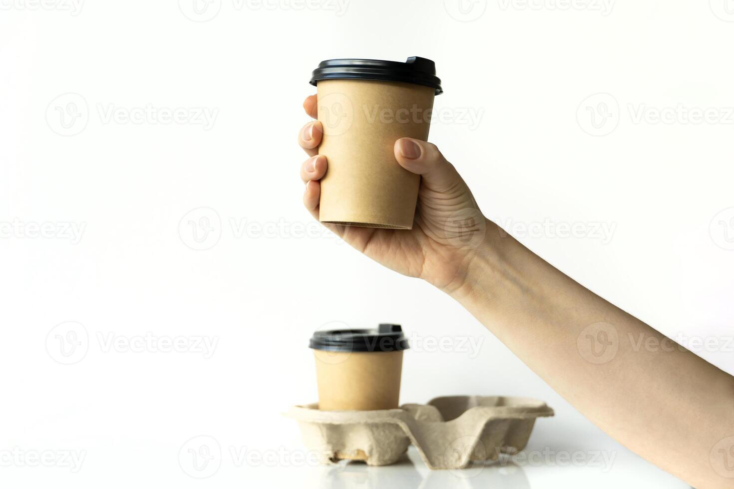 Takeaway paper coffee cups in woman hand with plastic lids and cardboard holder in cardboard holder on white background, eco friendly, biodegradable, mockup photo