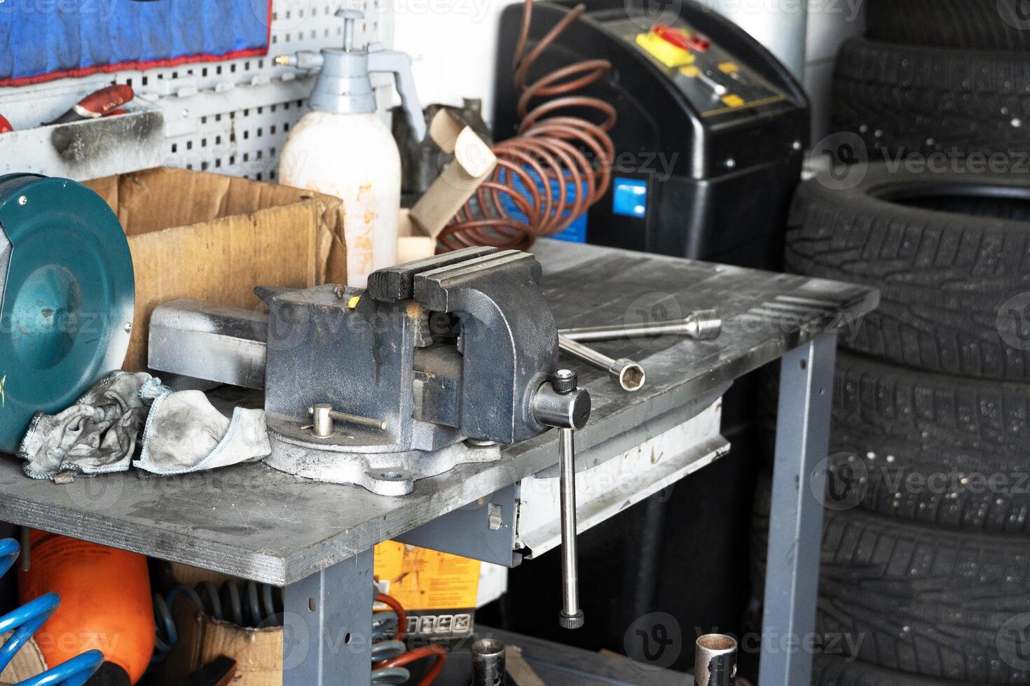 Mess on a working table with metallic tools and metal vice, tires pressure, garage workshop photo