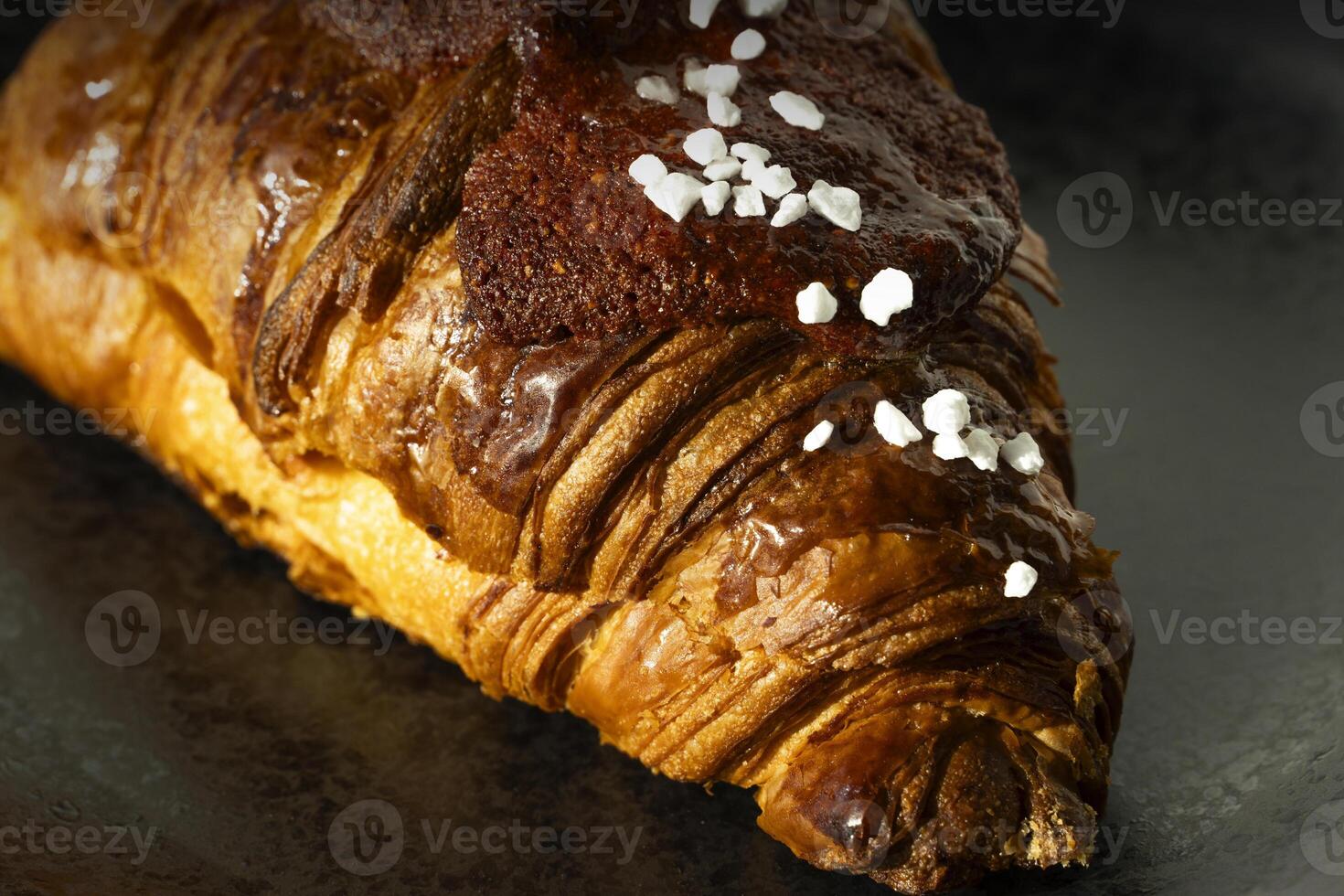 Freshly baked French pastry on black background with jam. Closeup photo. Buttered bread croissant on black photo