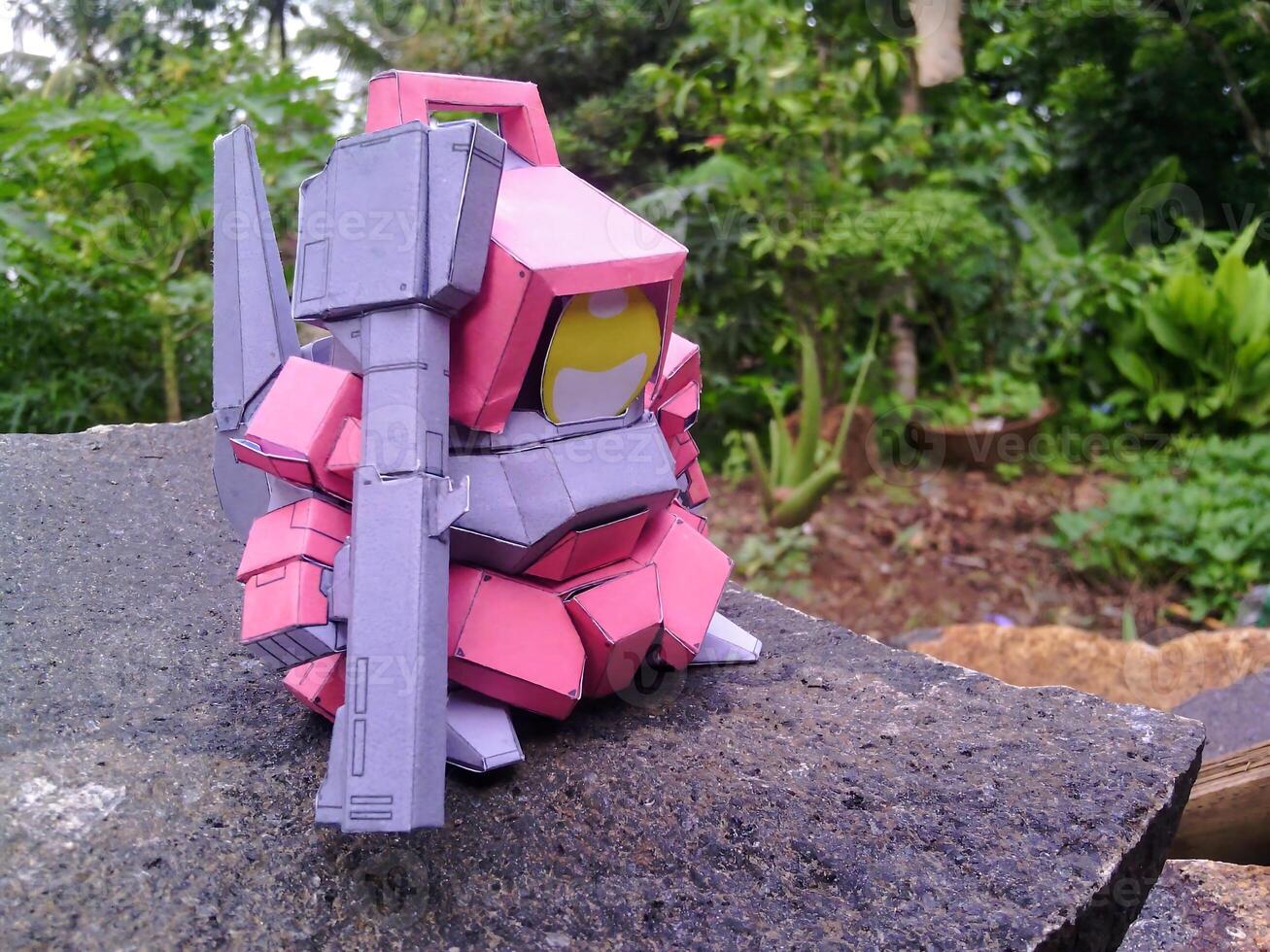 A paper model of a pink robot holding a gun photo
