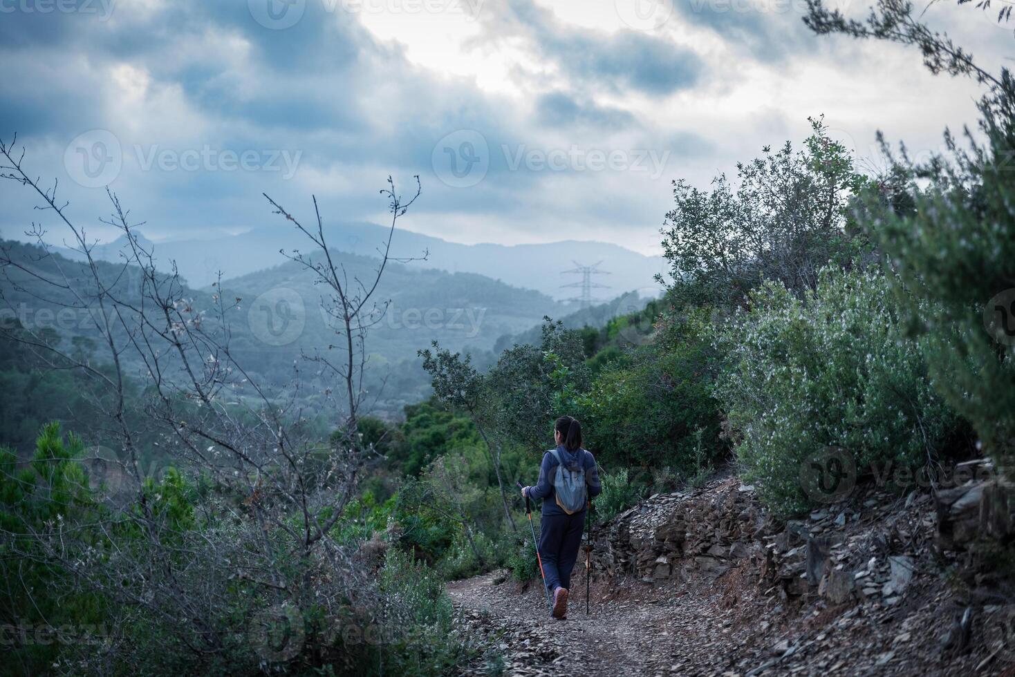 A hiker walks along a mountain path, taking in the natural beauty. photo