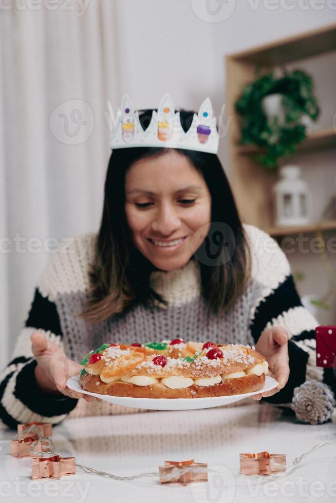 A smiling woman with a cardboard crown, about to taste the delicious roscon for Kings' Day. photo