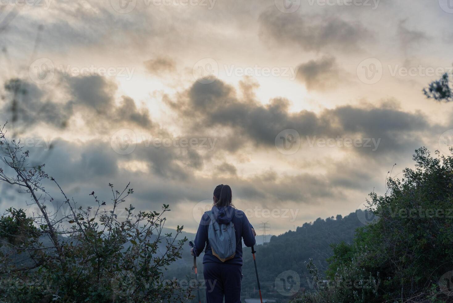 Hiker surrounded by trees, nature and a beautiful sky at sunset. photo