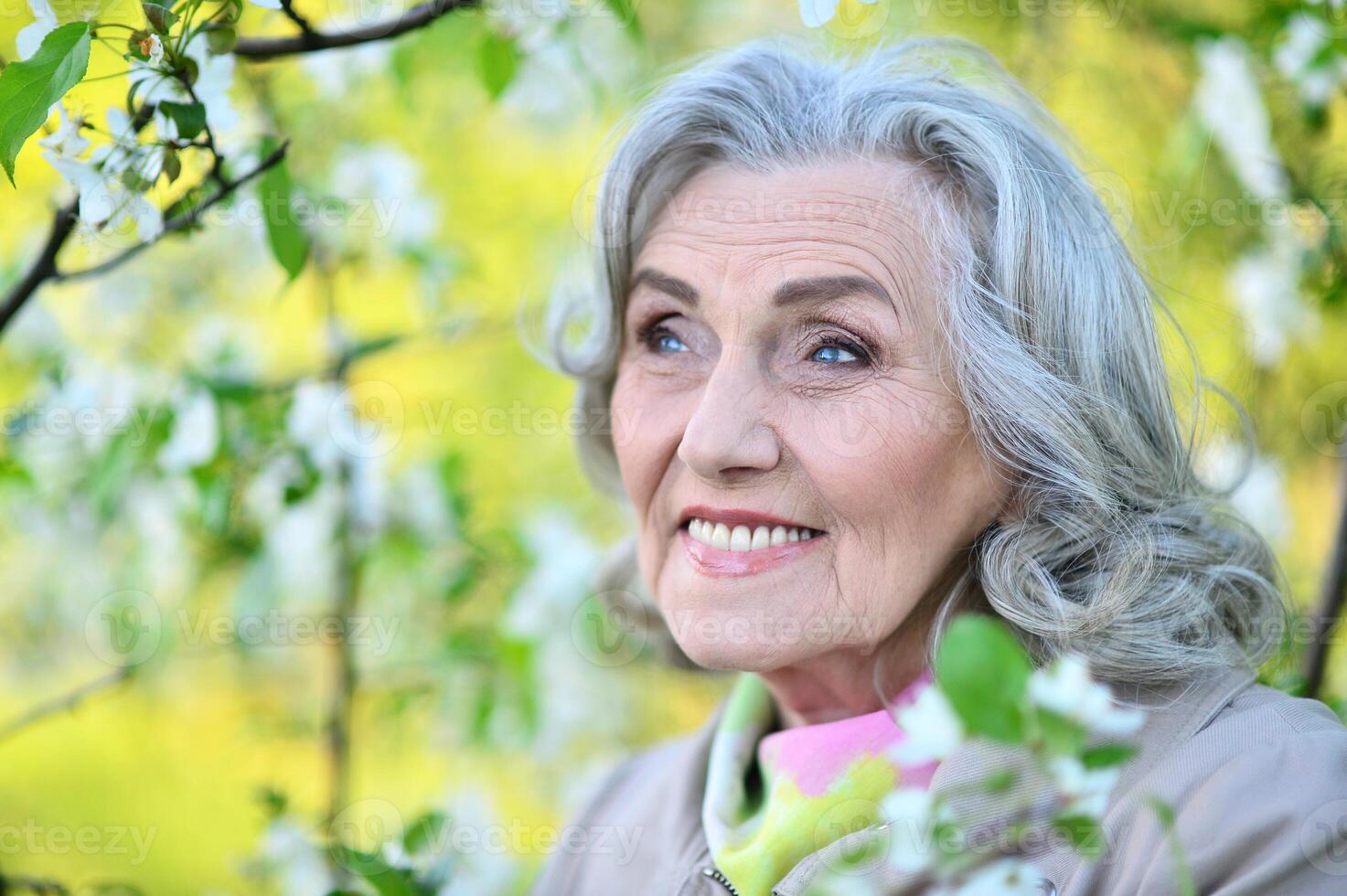 Portrait of happy senior beautiful woman in spring park photo