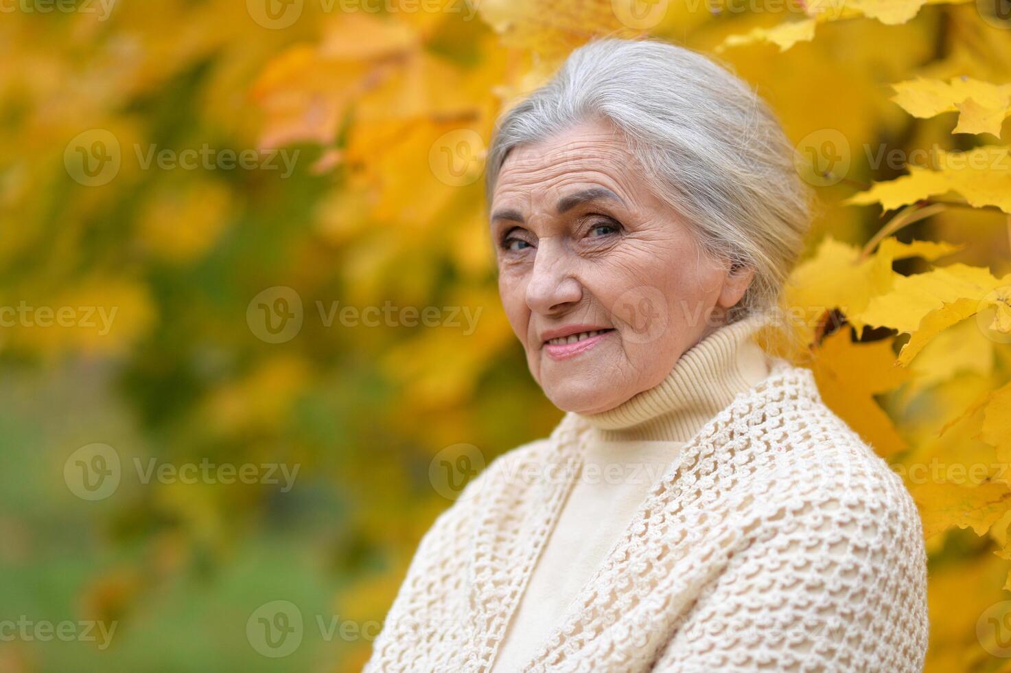 Senior nice woman walking in the park in autumn. photo
