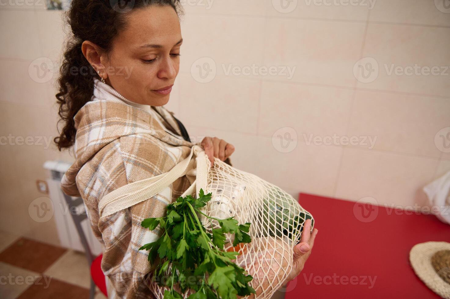 Woman carrying reusable eco-friendly shopping bag with groceries photo
