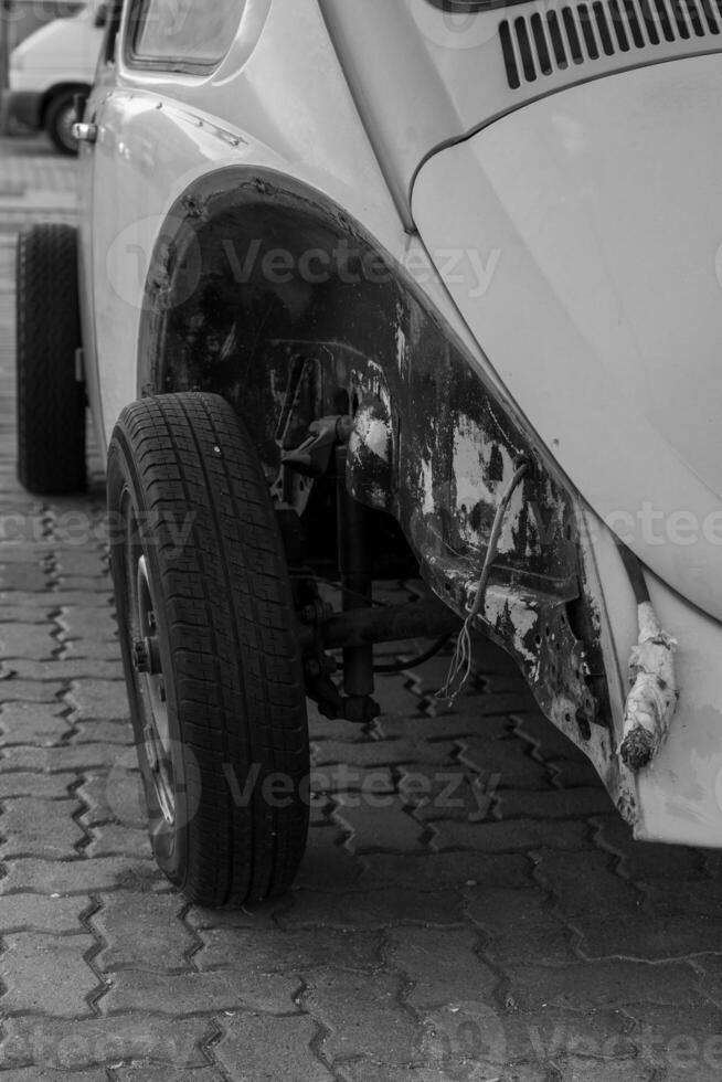 Damaged vintage car rests on paved surface, afternoon light revealing extensive bodywork damage photo