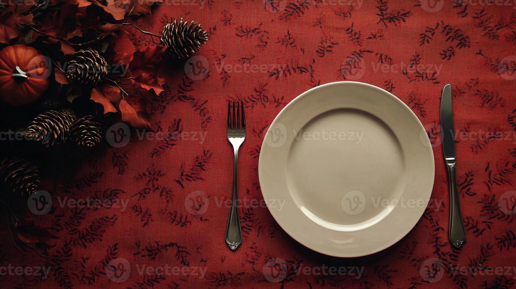 A white plate with a fork and knife on a red tablecloth photo