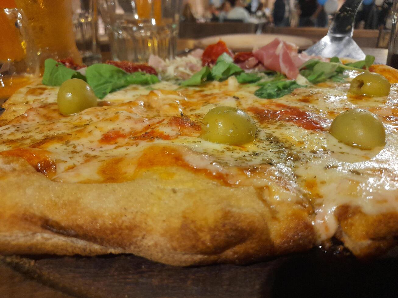 A pizza with olives and cheese on a wooden table photo