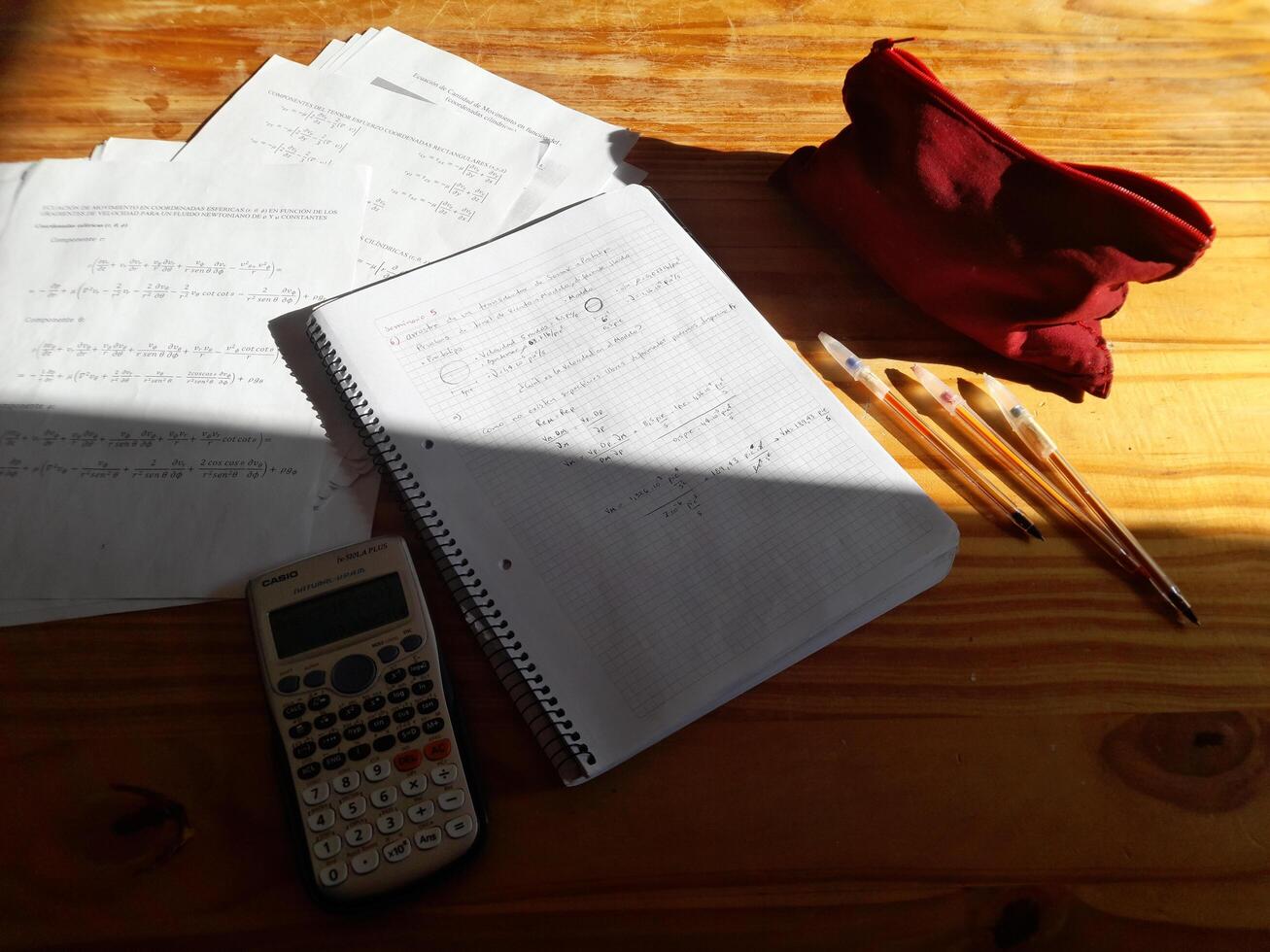 A calculator, a notebook, and a red bag on a table photo