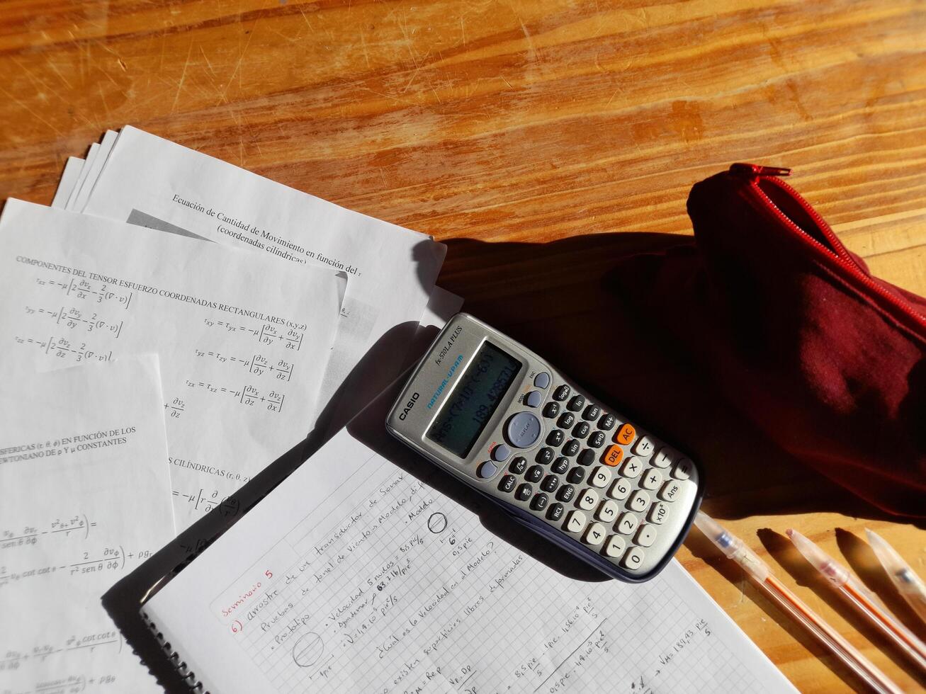 A calculator, pencils and papers on a desk photo