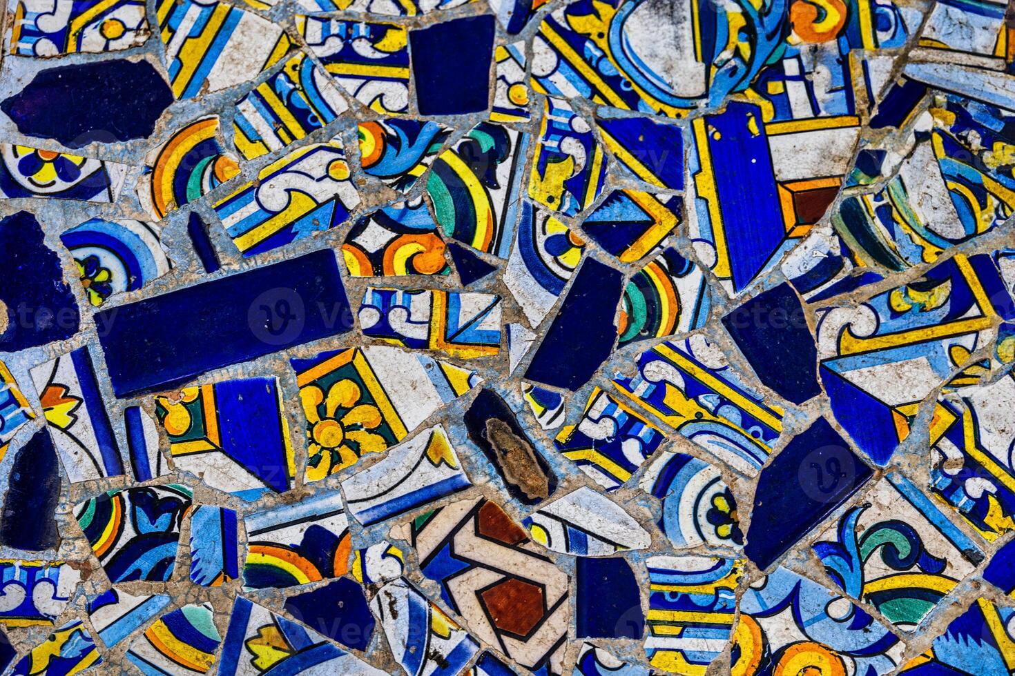 A collection broken of decorative ceramic tiles displays an array of intricate patterns and vibrant colors, including blues, reds, and greens photo