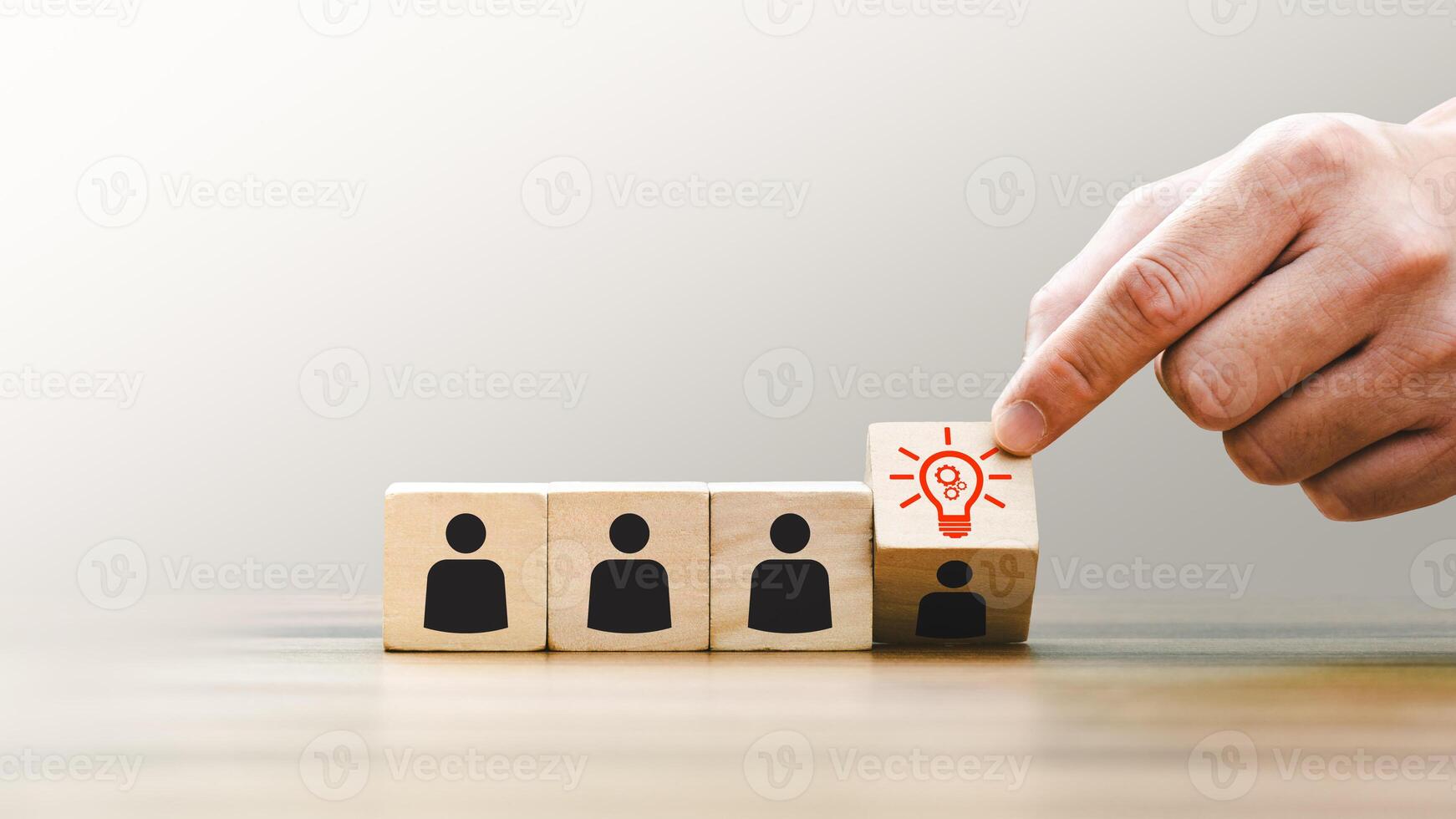 Hand Picking a Block with a Lightbulb Icon Representing Innovation New Ideas, Standing Out Among Wooden Blocks with People Icons, Symbolizing Leadership, Creative Solutions, Individuality in Teamwork photo