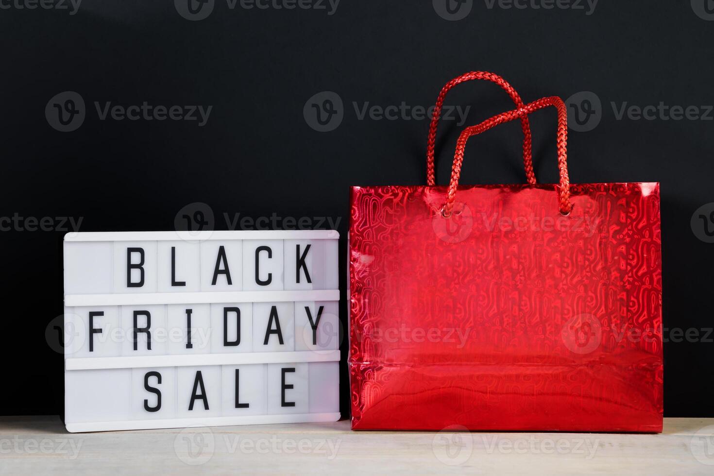 Black Friday sale. Red shopping bag and lightbox on a dark background. photo