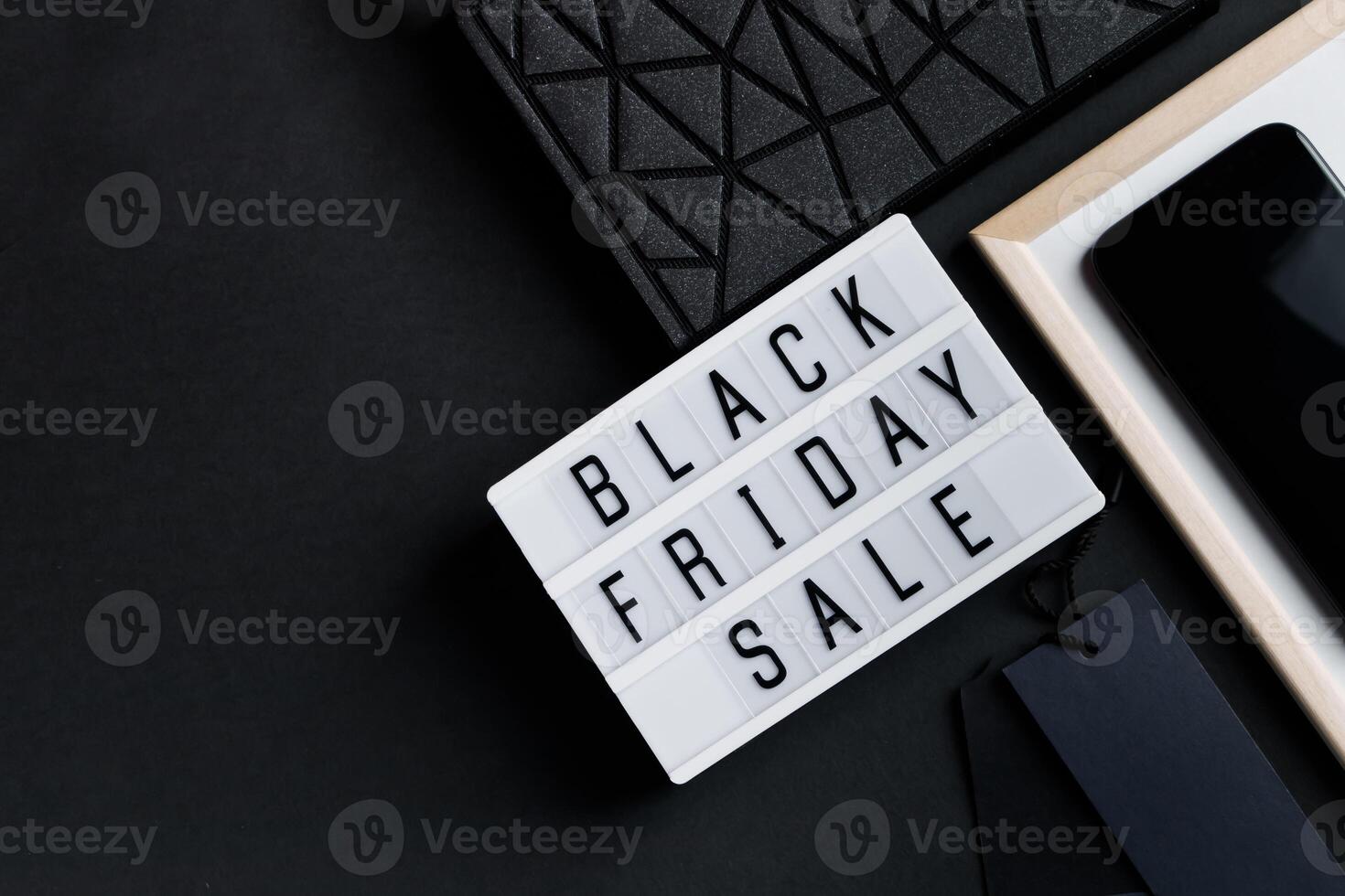 Black Friday online sale concept. Monochromatic flatlay on dark background. Smartphone and accessories. photo