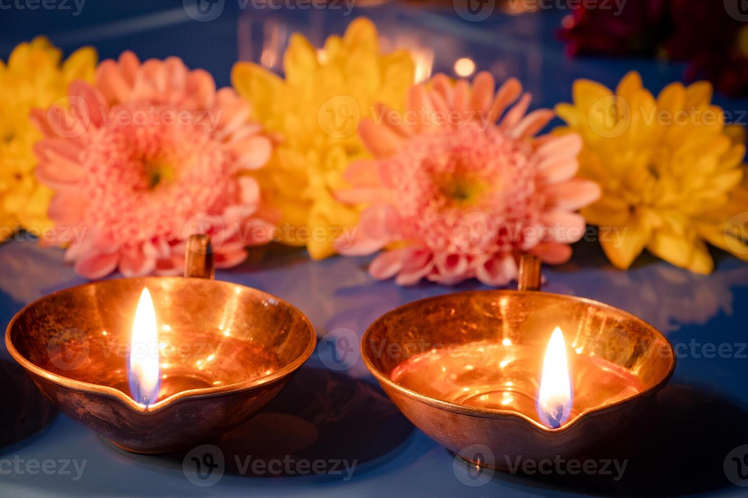 Happy Diwali. Burning diya oil lamps and flowers on blue background. Traditional Indian festival of light. photo