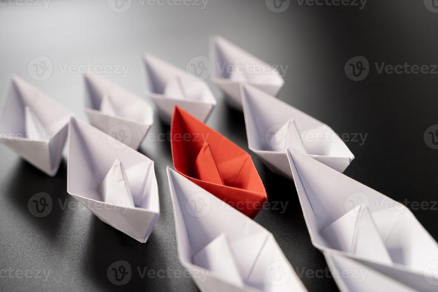 Row of paper ships on black background. Business concept of creative innovation and leadership. photo
