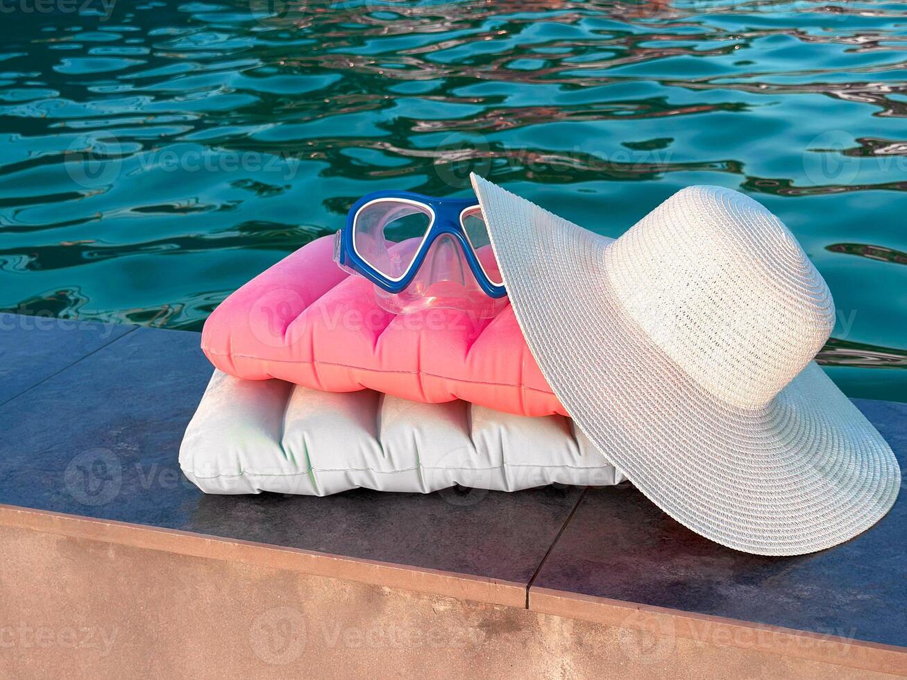 Snorkeling mask, inflatable pillows by the pool. Beach hat on the background of water. Diving mask. photo